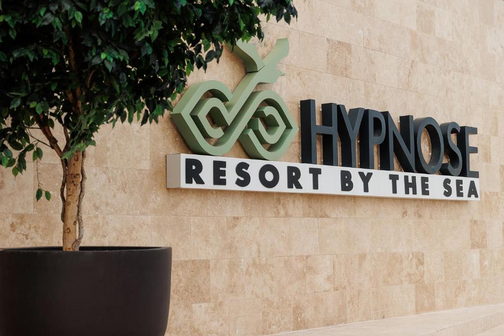 バドゥにあるHypnose Resortの海辺の現代リゾートの看板