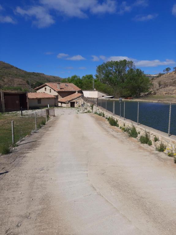 un camino de tierra junto a una valla y un cuerpo de agua en Molí d'en Pi, en Morella