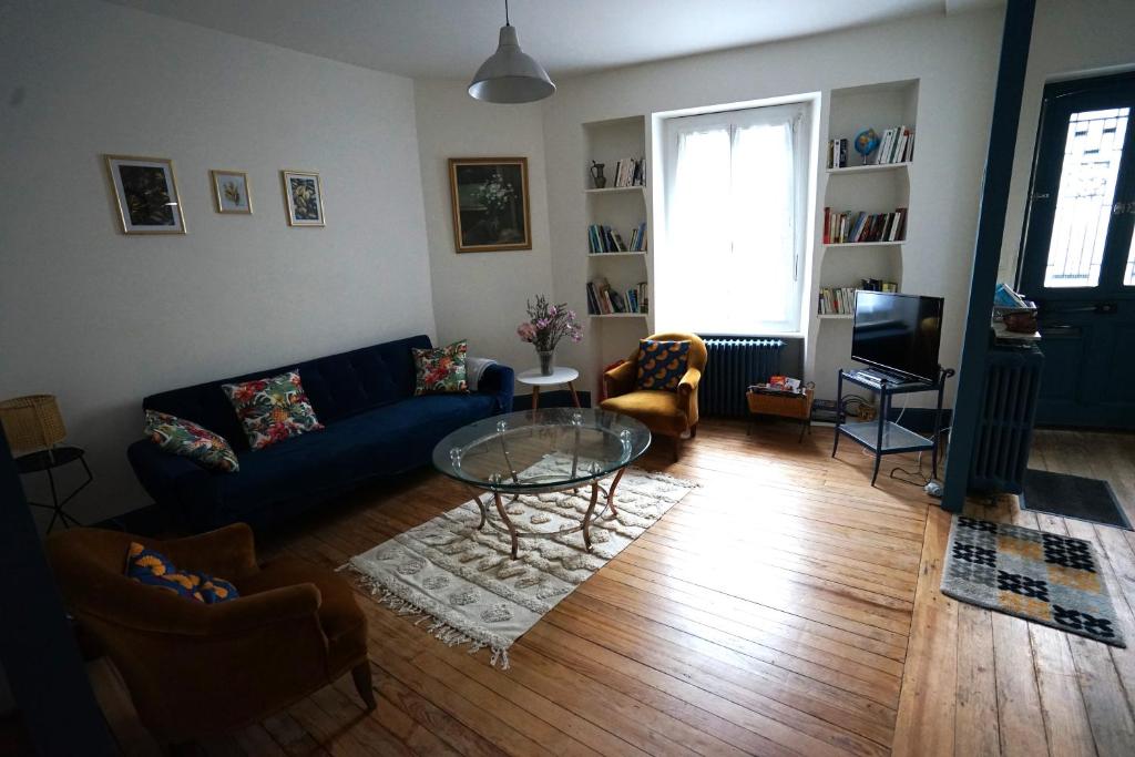 ein Wohnzimmer mit einem blauen Sofa und einem Glastisch in der Unterkunft La maison du Thoré in Saint-Amans-Valtoret