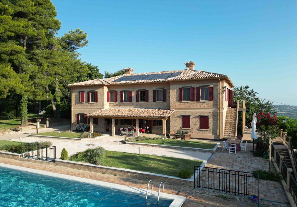 een groot huis met een zwembad ervoor bij Villa Fonti in Orciano di Pesaro