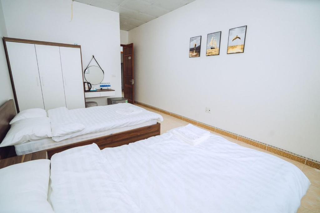 two beds in a room with white walls at Dung Hà Hotel 
