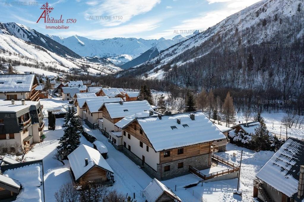 a village covered in snow with mountains in the background at Appartement neuf avec une grande terrasse au cœur du village - 6 personnes in Saint-Sorlin-dʼArves