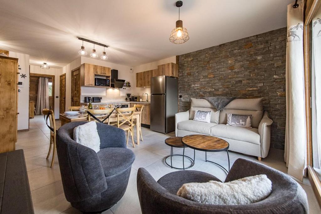 a living room with a couch and chairs and a kitchen at Appartement neuf au cœur du village - 6 personnes in Saint-Sorlin-dʼArves