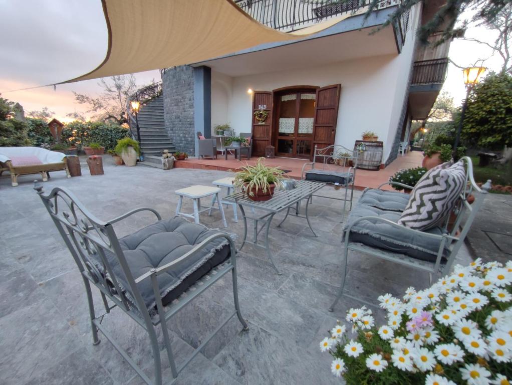 une terrasse avec des chaises, une table et des fleurs dans l'établissement Casa degli Ulivi Etna, à Ragalna