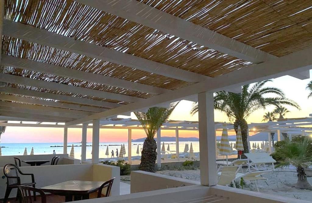 un patio con mesa y sillas y la playa en Lido Di Alghero Rooms on the Beach, en Alghero