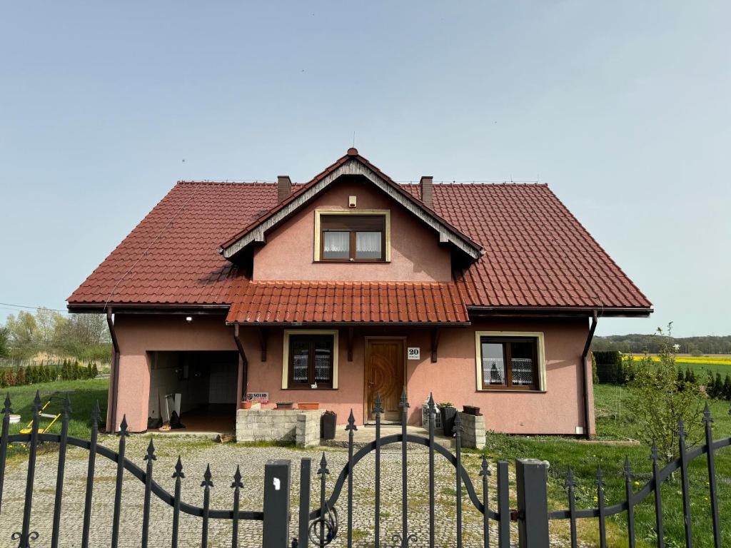 una casa rosa con una valla delante en Dom Krotoszyce, en Krotoszyce