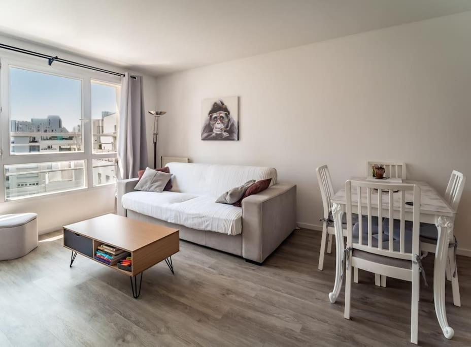 ein Wohnzimmer mit einem Sofa und einem Tisch in der Unterkunft Skyview appartement la Défense in Courbevoie