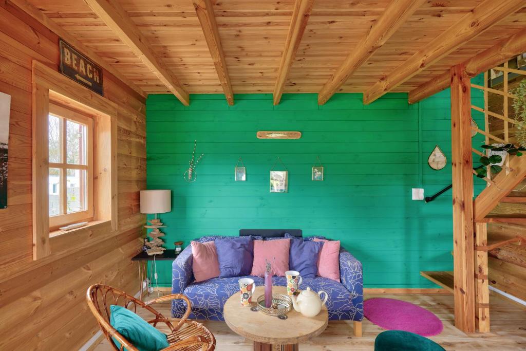 a living room with a blue couch and a green wall at Paisible et insolite chalet pour 4 personnes a Penmarch in Penmarch