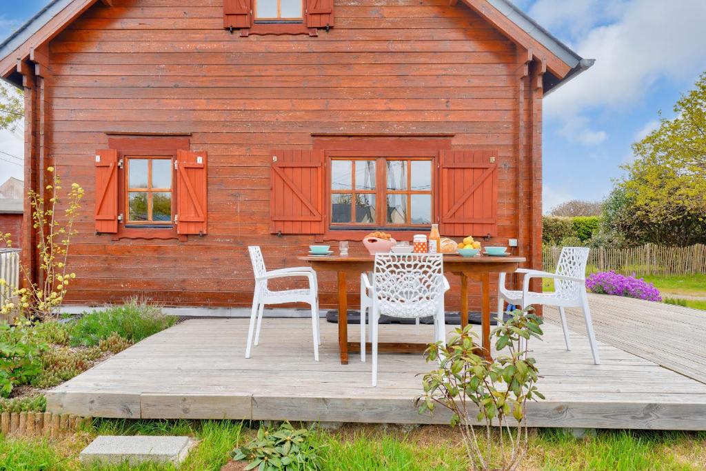 a table and chairs on a deck in front of a cabin at Paisible et insolite chalet pour 4 personnes a Penmarch in Penmarch