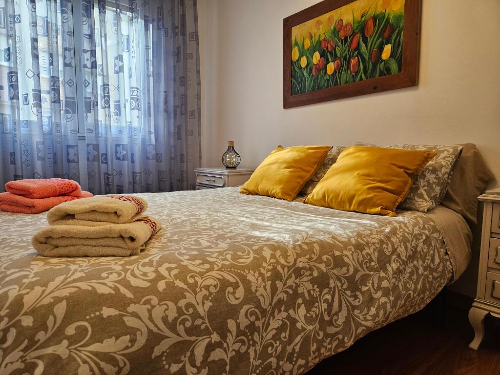 Un dormitorio con una cama con almohadas amarillas y una pintura en Casa Lantoxana Quiet and fully-equipped , ideal for families, en Gijón