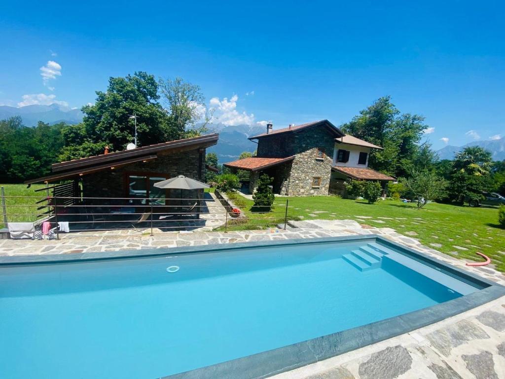 a villa with a swimming pool in front of a house at Tenuta Pozzi in Colico