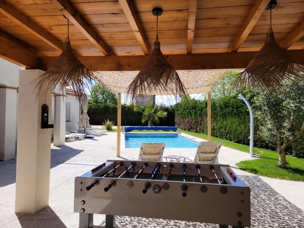 a ping pong table in a patio with a pool at Villa piscine chauffée babyfoot pétanque ping-pong in Bon-Encontre