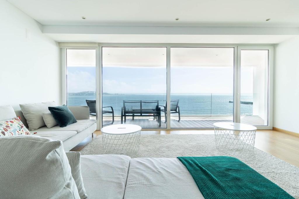 a living room with a couch and a view of the ocean at Akicity Jamor Selected in Cruz Quebrada