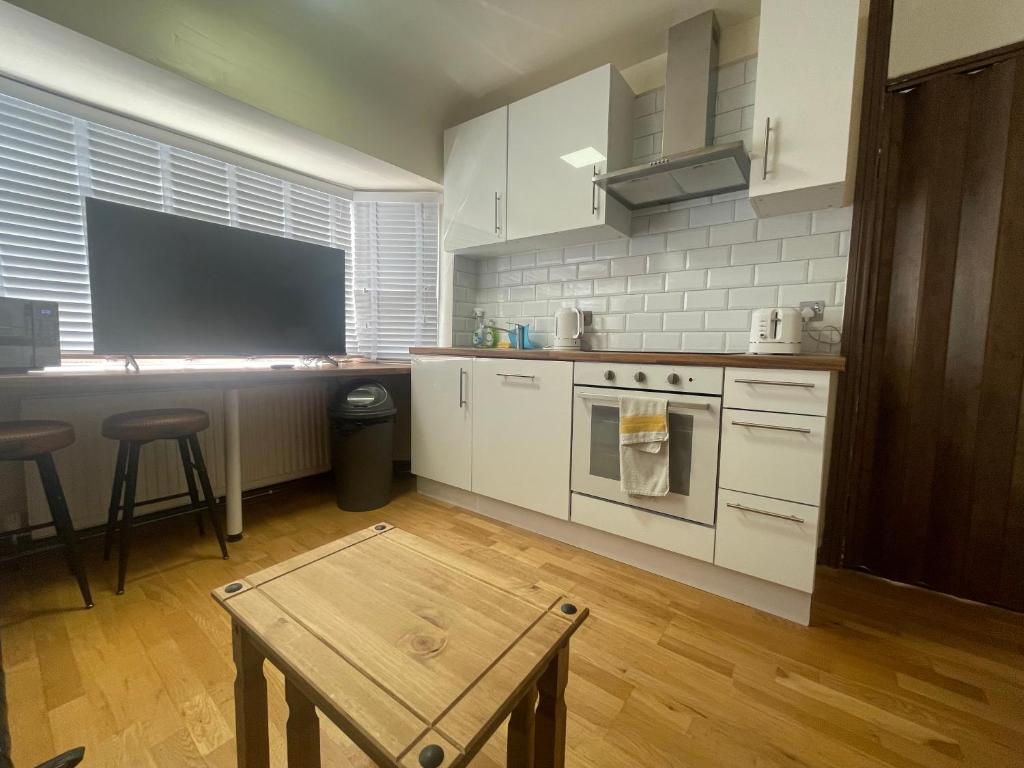 cocina con electrodomésticos blancos y mesa de madera en 2 Bed Flat near Heathrow Airport & Elizabeth Line en Hayes