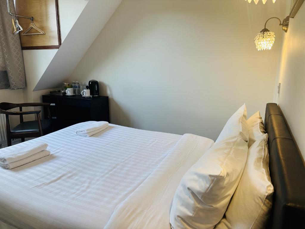 1 dormitorio con 1 cama con sábanas y almohadas blancas en woodcock inn, en Felbridge