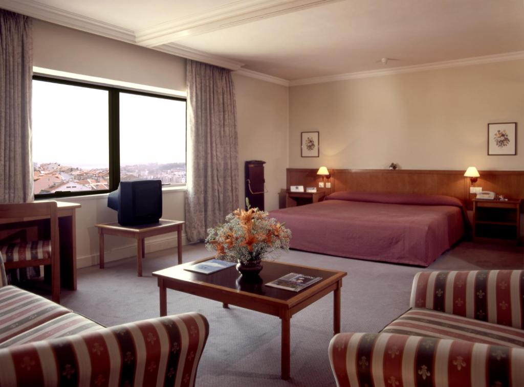 リスボンにあるAparthotel VIP Executive Suites do Marquêsのベッドとテーブルが備わるホテルルームです。