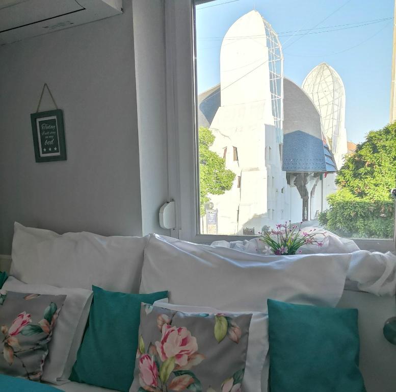 Sofá blanco con almohadas frente a una ventana en Centrum Luxus Apartman en Makó