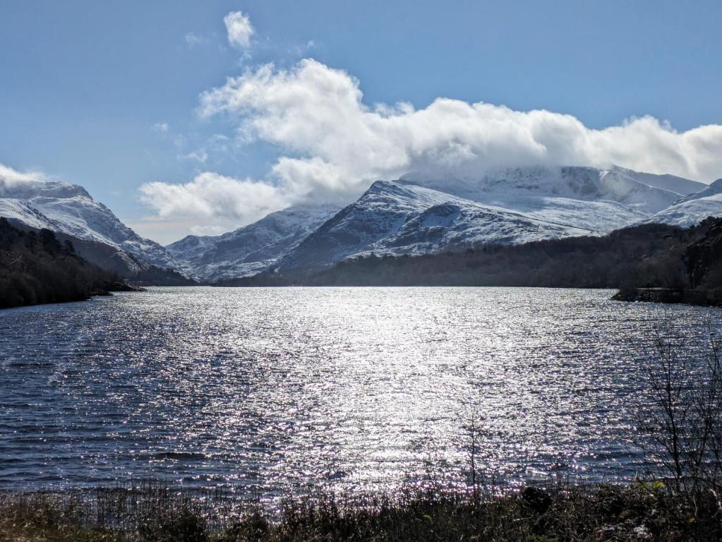 a large lake with snow covered mountains in the background at Ty Madog in Cwm-y-glo