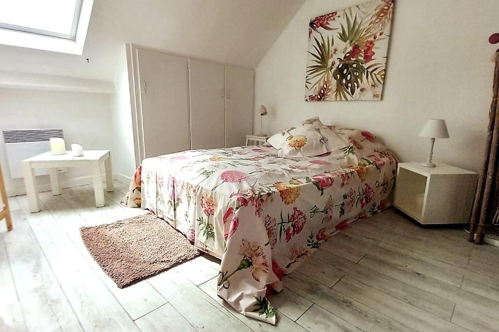 una camera da letto con un letto con copriletto floreale di Le Cocon rouge - studio en plein centre historique a Lamballe