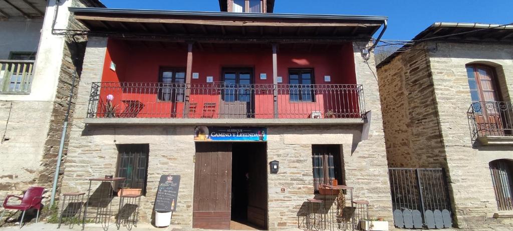 a red building with a balcony and a door at Camino y Leyenda in Trabadelo