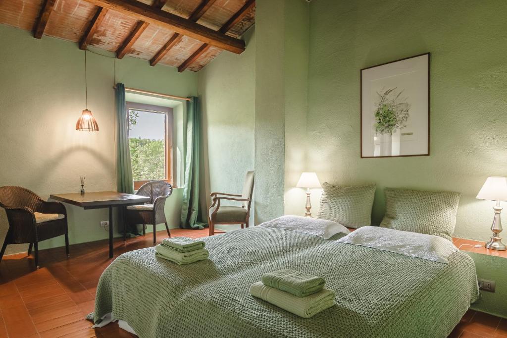 Un dormitorio con una cama con paredes verdes y una mesa. en Podere L'Erbolario, stylish villa with private pool and olive garden., en Scrofiano