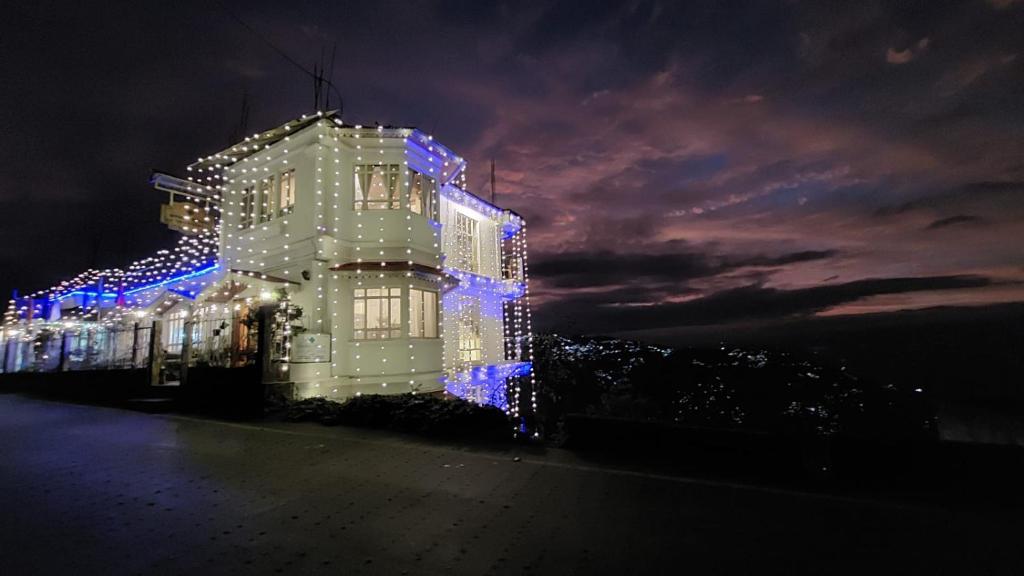 a building with christmas lights on it at night at Lamahatta Residency in Darjeeling