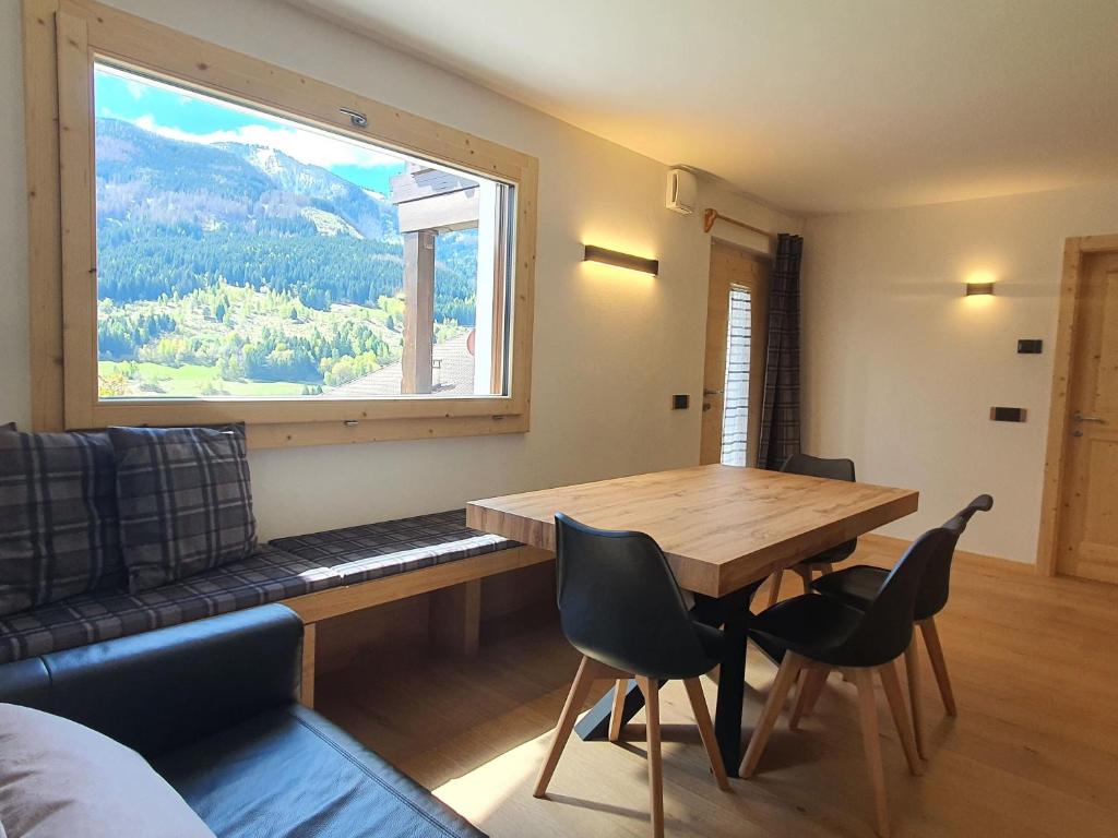 Un comedor con una mesa y un gran ventanal. en Casa Paolina - Alpine Stay Apartments, en Tesero