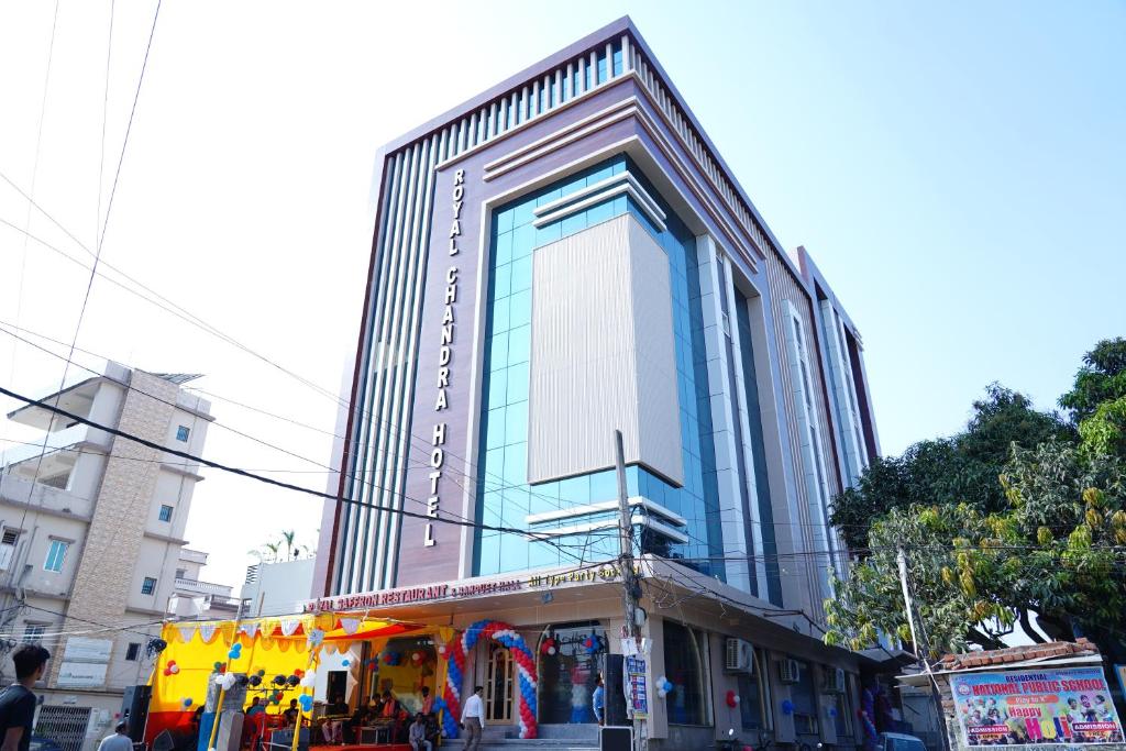 Um edifício alto com um autocarro amarelo à frente. em Royal Chandra Hotel em Patna