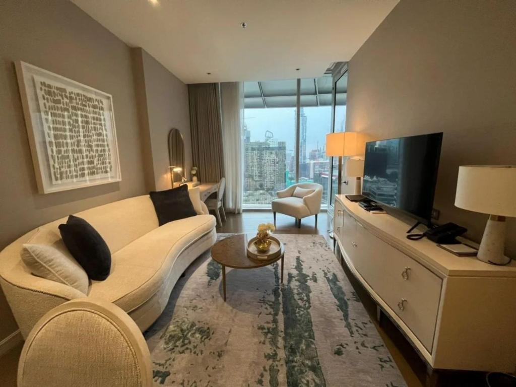 ein Wohnzimmer mit einem weißen Sofa und einem TV in der Unterkunft Chit Lom, Siam BTS, Perfect Best Location High Floor Sleeps 4 81sqm in Bangkok