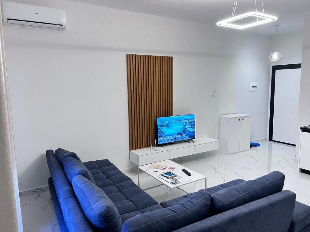 een woonkamer met een blauwe bank en een tv bij Prime Luxury Apartments in Lushnjë