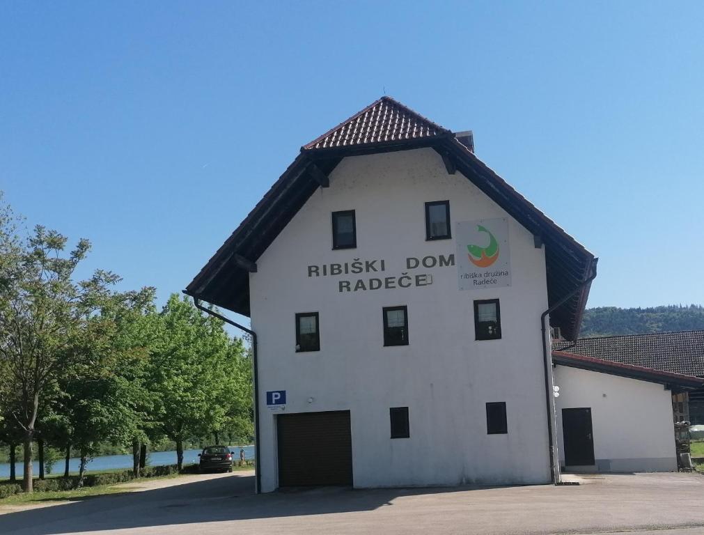 a white building with a sign on the side of it at Ribiški dom Radeče in Radeče