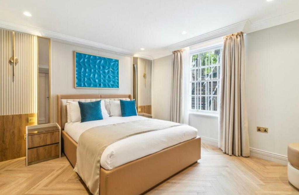 a bedroom with a large bed with blue pillows at Luxury 2 bed Apartment in London