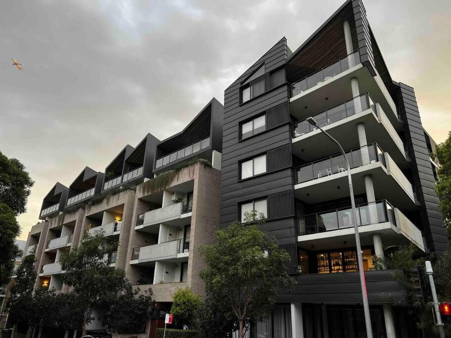 ein großes schwarzes Gebäude mit Bäumen davor in der Unterkunft Exquisite Inner City Modern 1 Bedroom Apt in Sydney