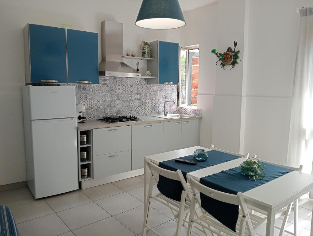 una cucina con armadi blu, tavolo e sedie di villa Amelie a Fondachello