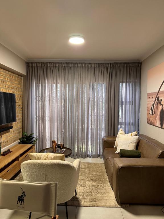 uma sala de estar com um sofá e cadeiras e uma televisão em Aries self-catering Unit em Centurion