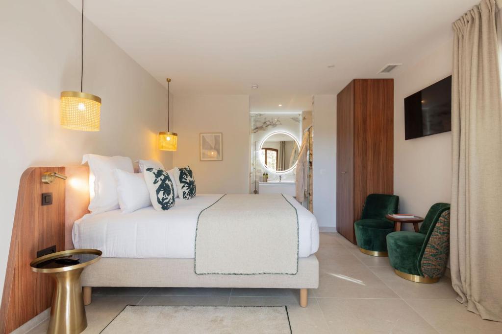 a bedroom with a white bed and a green chair at La Bastide Bourrelly - Mathias Dandine in Cabriès