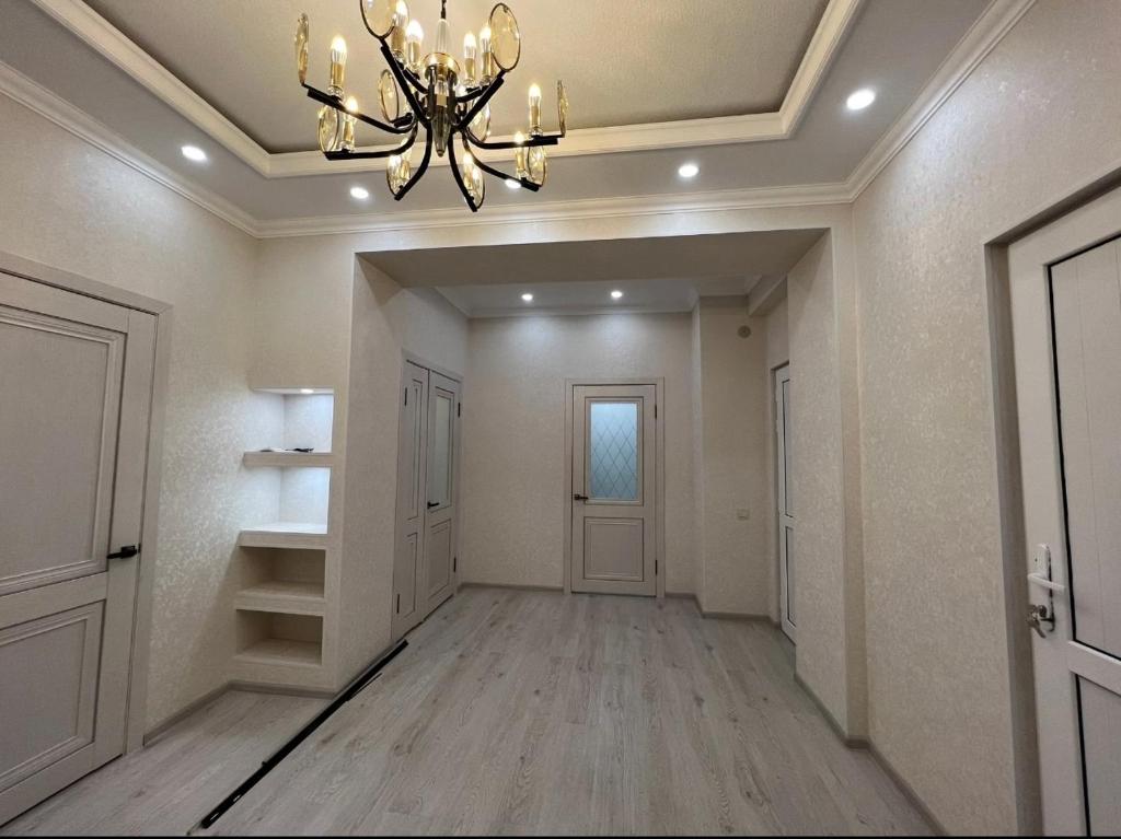 un pasillo vacío con una lámpara de araña en una casa en Квартира на Мурас Ордо, en Osh