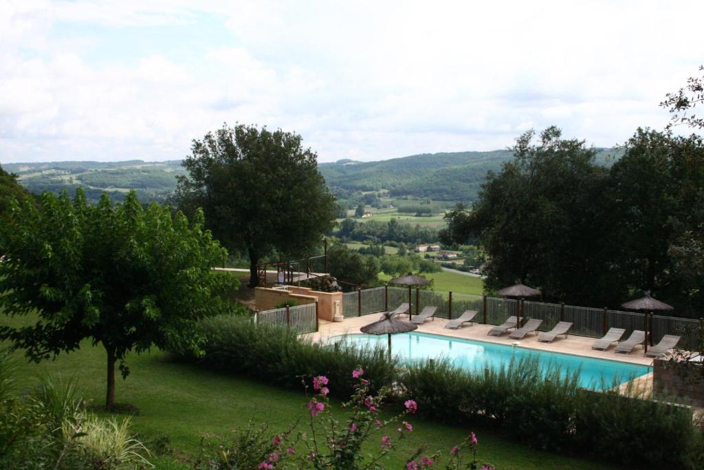 une vue sur une piscine avec des chaises et des arbres dans l'établissement Gîtes la Palombière La Mélonie, à Bézenac