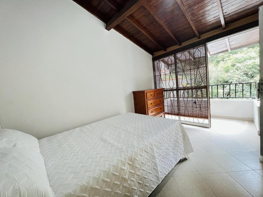 a bedroom with a white bed and a window at Casa Céntrica a 5 min Metro y Mayorca in Envigado