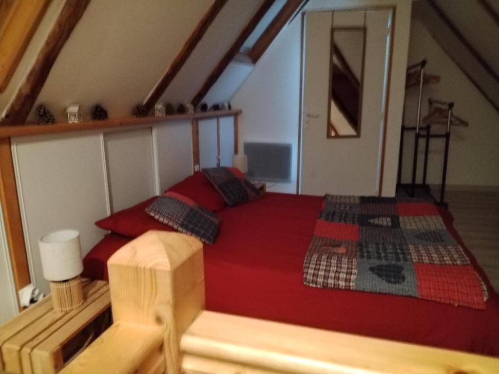 sypialnia z czerwonym łóżkiem na poddaszu w obiekcie APPARTEMENT EN DUPLEX " LA DORDOGNE" dans maison individuelle w mieście Mont-Dore
