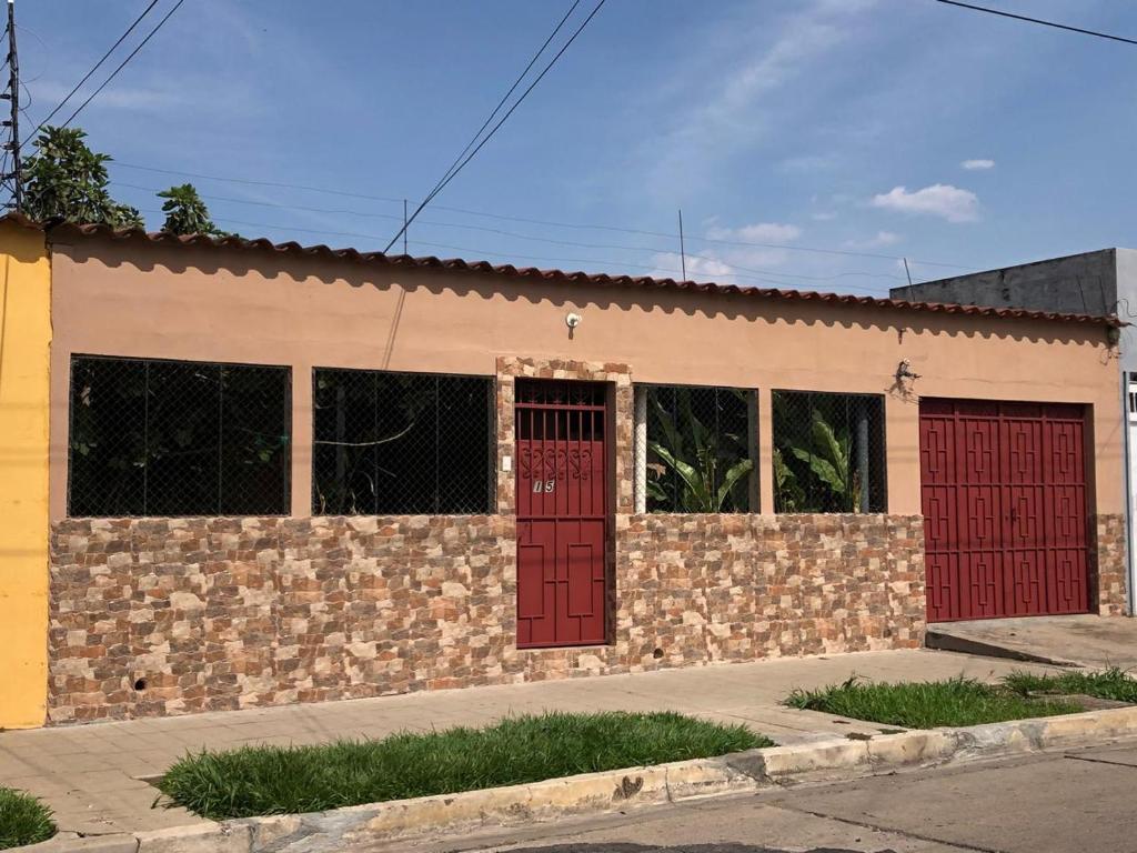 een bakstenen gebouw met rode deuren en ramen bij Hostal Notas y Puntadas a 1,2 Kms del Centro Historico de Santa Ana in Santa Ana