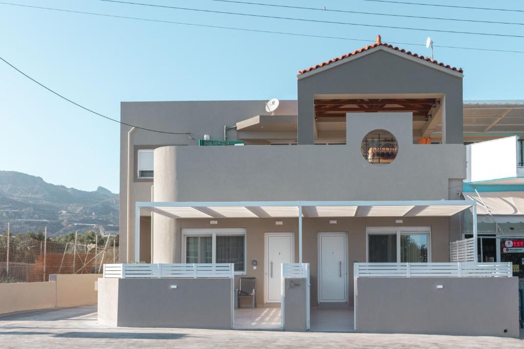 a white house with a fence in front of it at Harmony Luxury 1 in Ierápetra