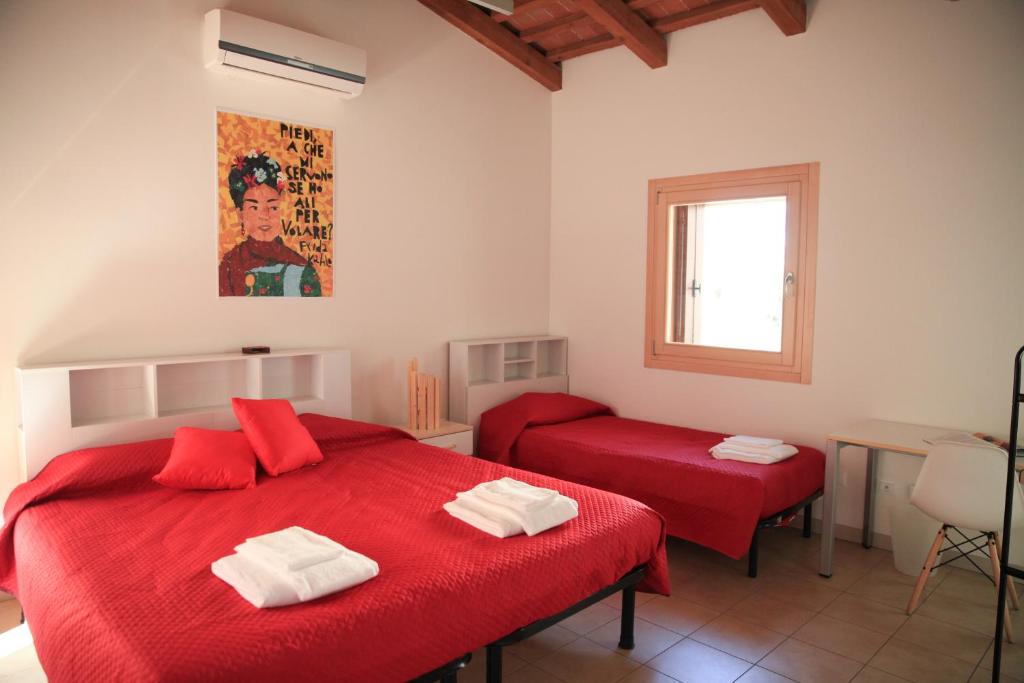 a bedroom with two red beds and a window at Guesthouse Villa Fabris in Thiene