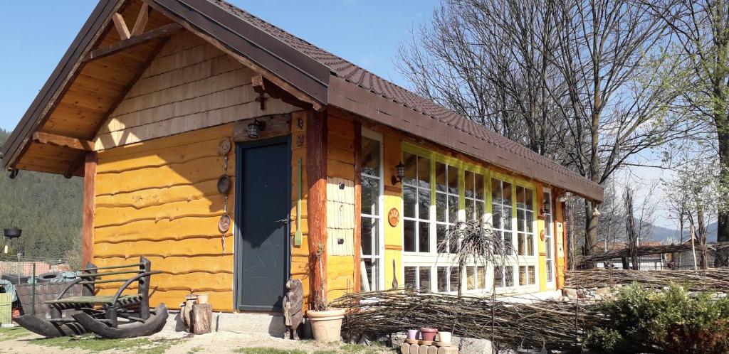 a log cabin with a yellow door and windows at Mica fermă veselă in Câmpulung Moldovenesc