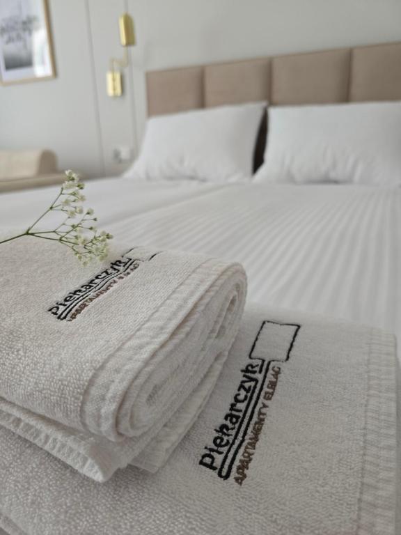 a bed with two white towels on top of it at Apartamenty Piekarczyk - Elbląg in Elblag