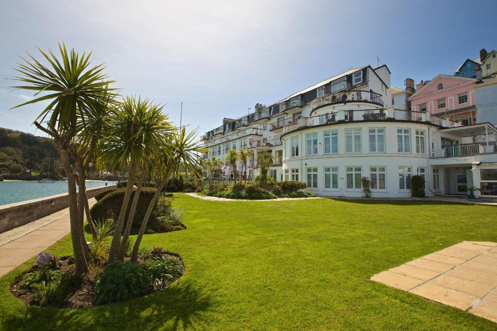 a large white building with palm trees in a yard at 4 The Salcombe in Salcombe