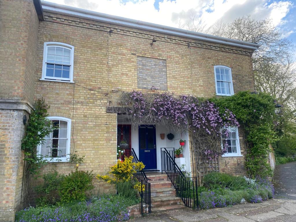 una casa in mattoni con porta blu e fiori di The Old Mill Cottage a Fakenham
