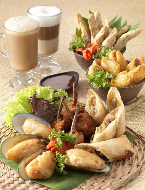 A styled platter combines fried appetisers, seafood, meat, dipping sauce, and two drinks.