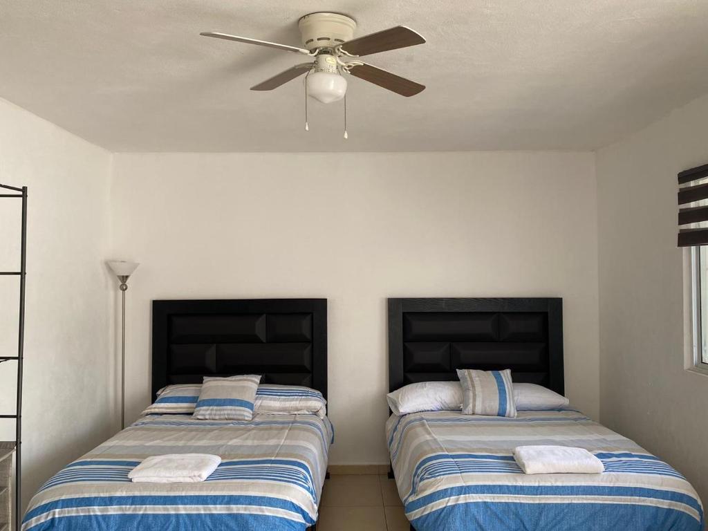 two beds in a room with a ceiling fan at Apartamentos Amplios Alfa # 238 in Monterrey