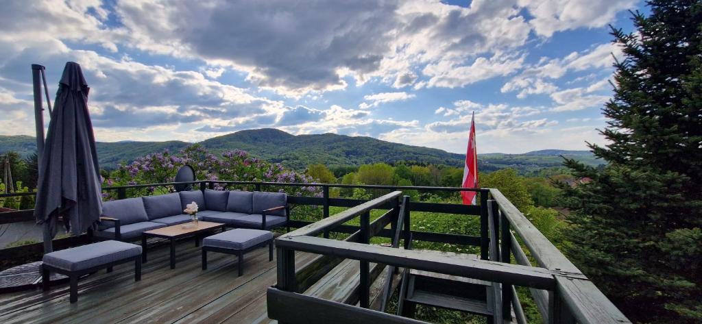 a deck with a table and chairs and a view of mountains at Dworek Wołyński - Winnica Zegartowice 